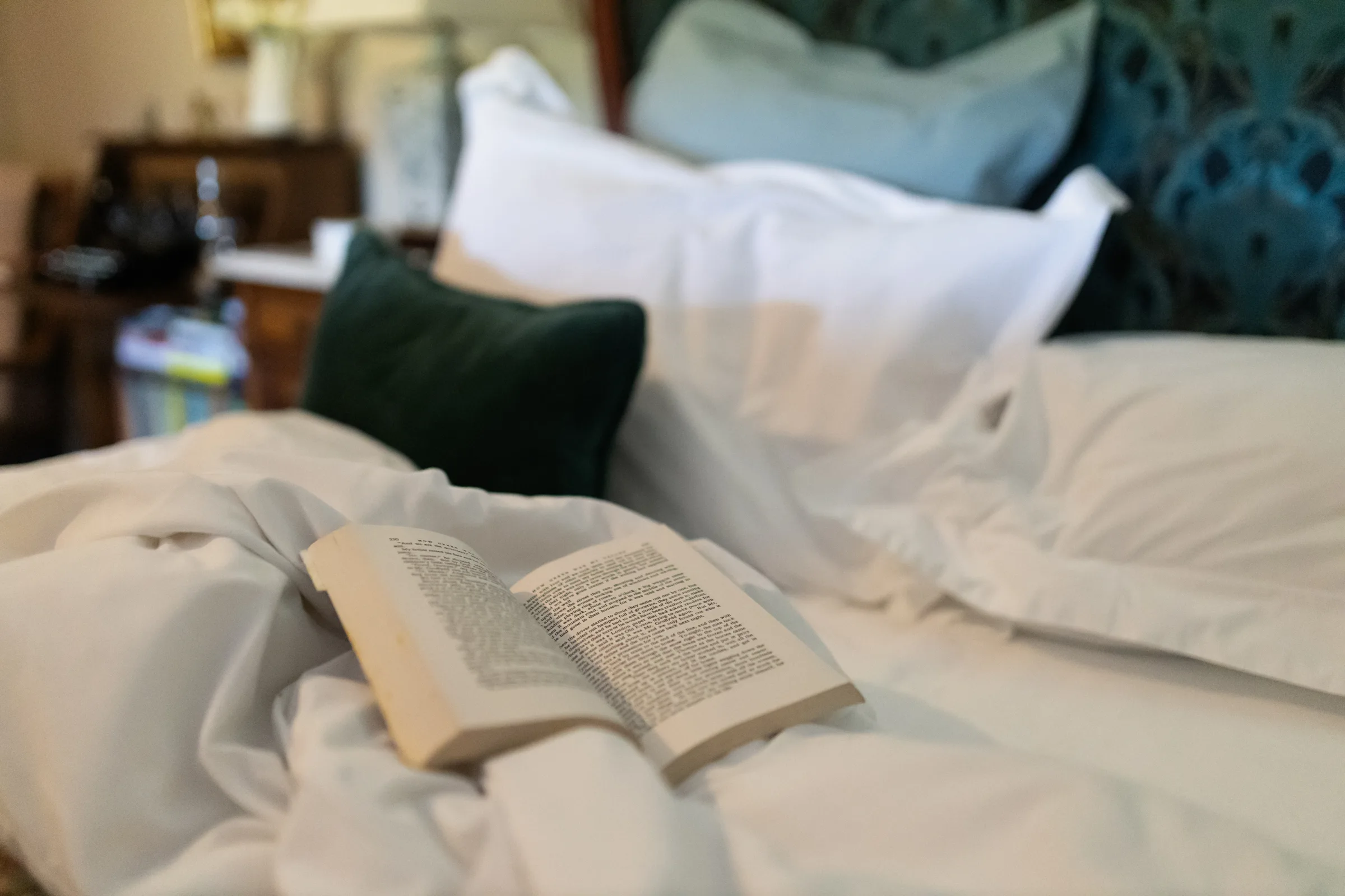 Open book on a bed with soft linens inside the master bedroom at Gablebach cottage