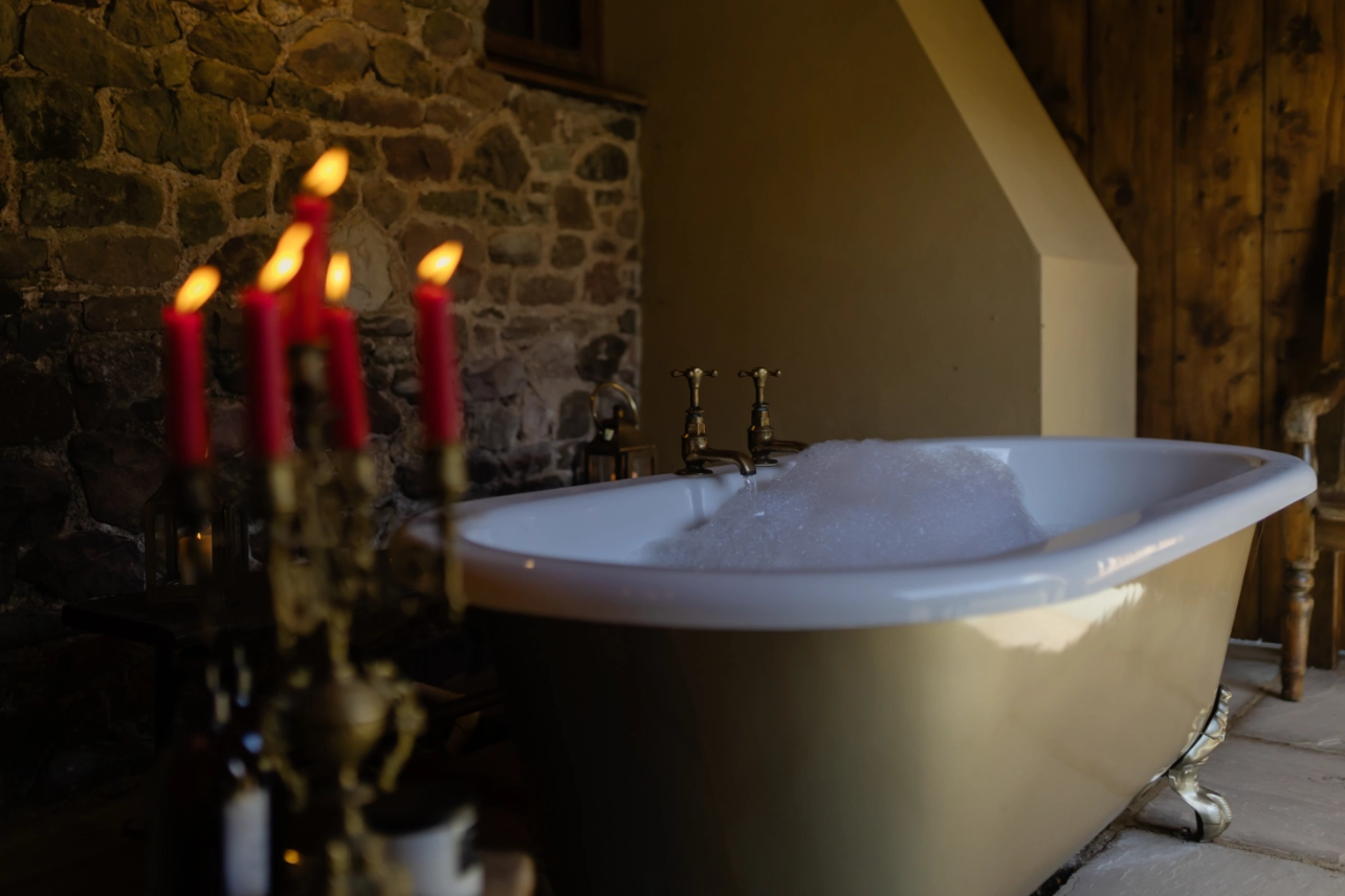 Covered outdoor hot tub at Y Golchdy overlooking the Welsh countryside at golden hour with champagne glasses ready to enjoy.
