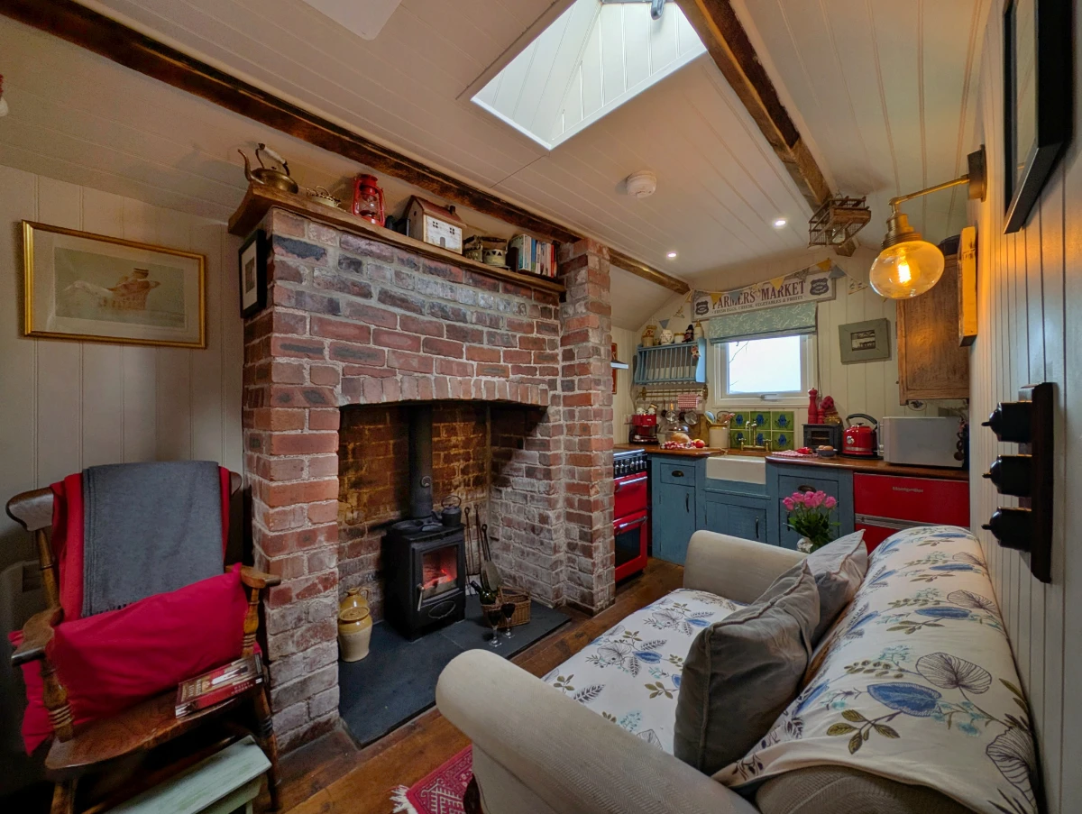 Cosy living space at Y Golchdy with comfortable seating, wood burner and rustic cabin character.