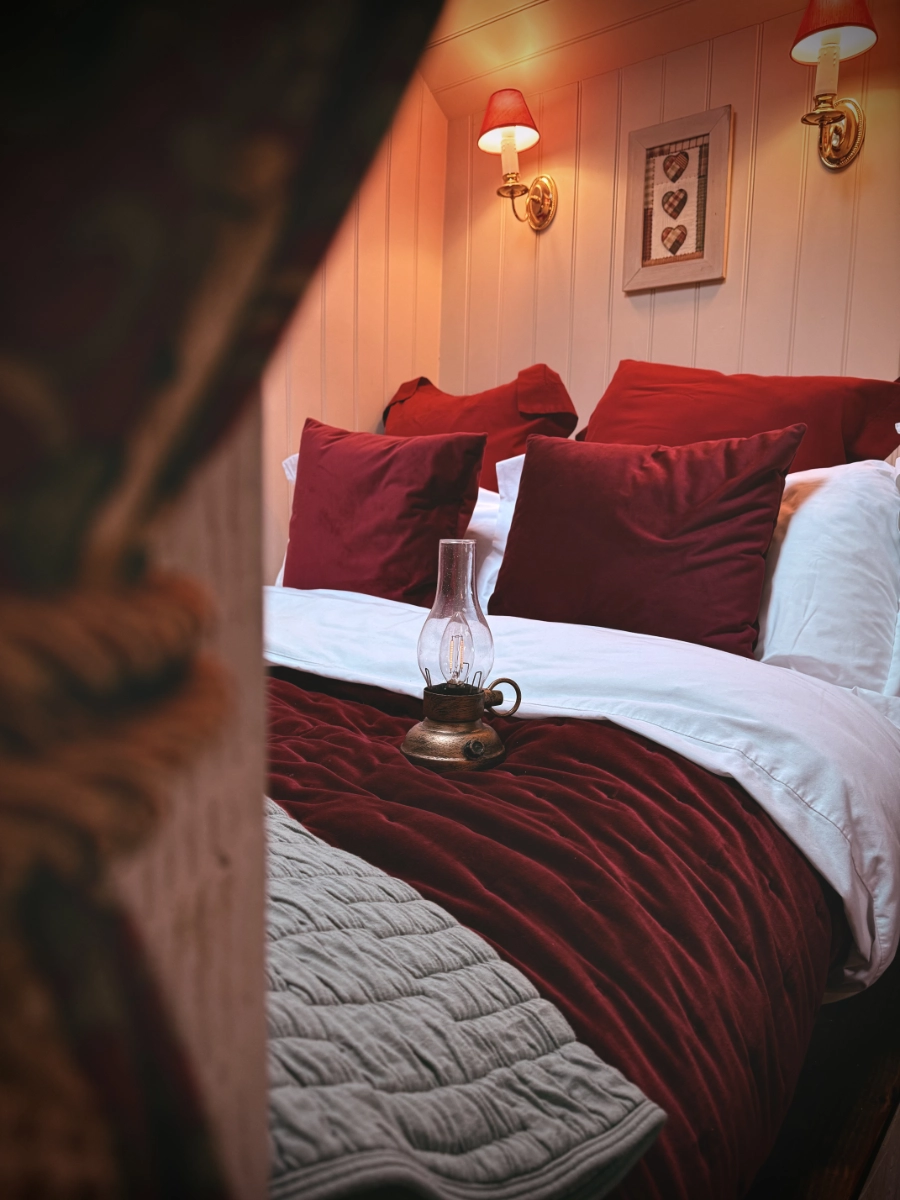 Cosy bedroom at Y Golchdy with inviting double bed, warm lighting and romantic cabin atmosphere.