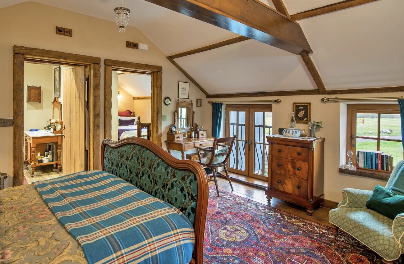 Bedroom at Gablebach Cottage with vintage dressing table, French doors and views into the en-suite bathroom and shower room