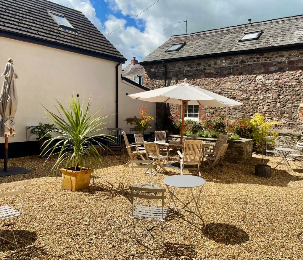 Sunlit courtyard terrace at Y Castell in Llangadog with outdoor seating and stone gravel.